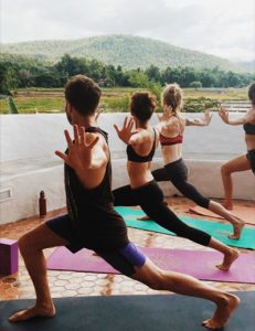 Yoga Students from the Wild Rose Yoga Studio and Pranaya Yoga Teacher Training in Chiang Mai Thailand practising on the Veranda of the Mala Dhara Eco Resort while overlooking the rice fields.