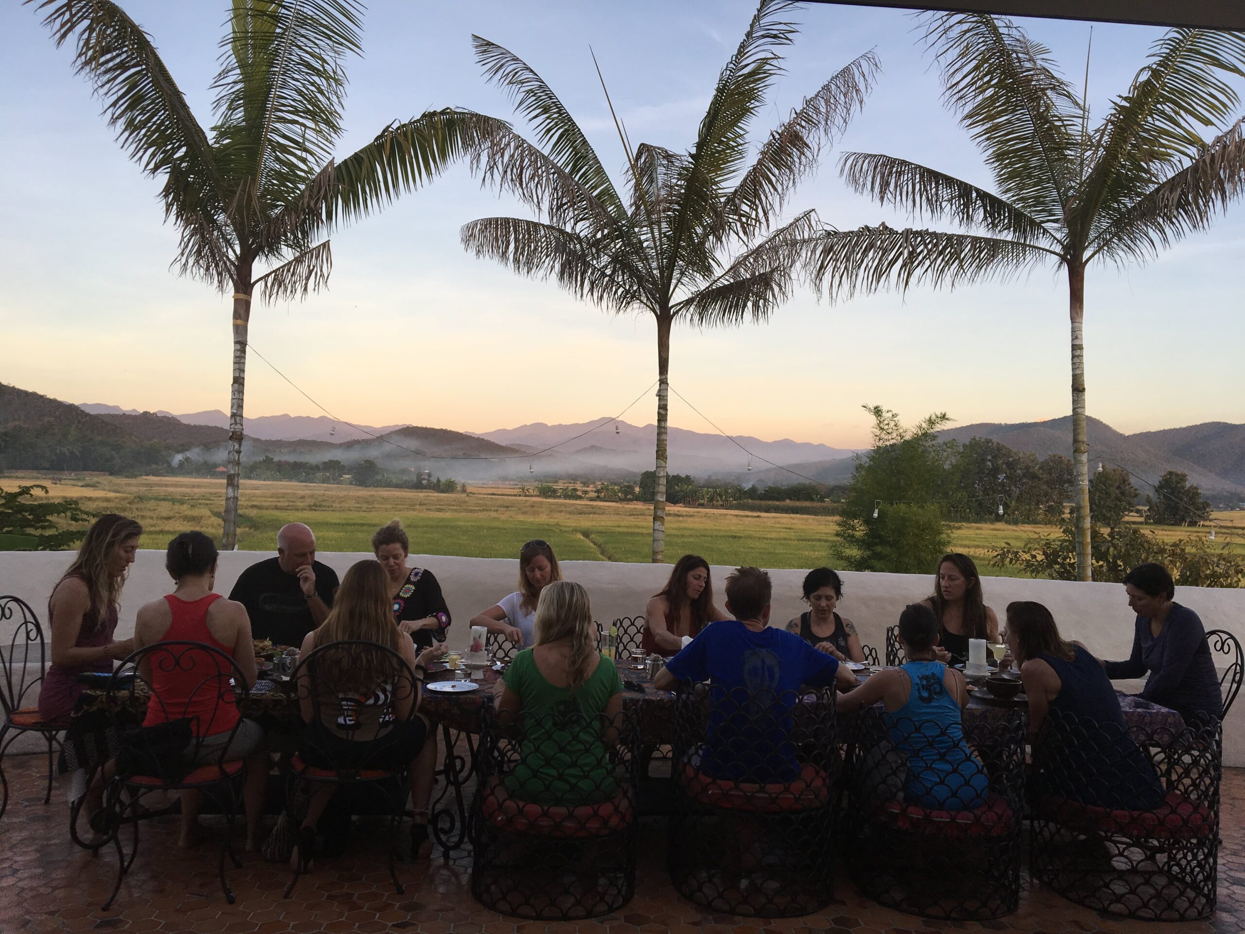 Chiang Mai yoga retreat group enjoying plant based vegan mean on veranda with view of rice fields at Mala Dhara