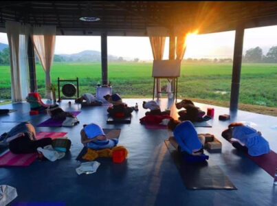 Early morning yoga at sunrise in rice fields at Mala Dhara Yoga Retreat Center in Chiang Mai Thailand